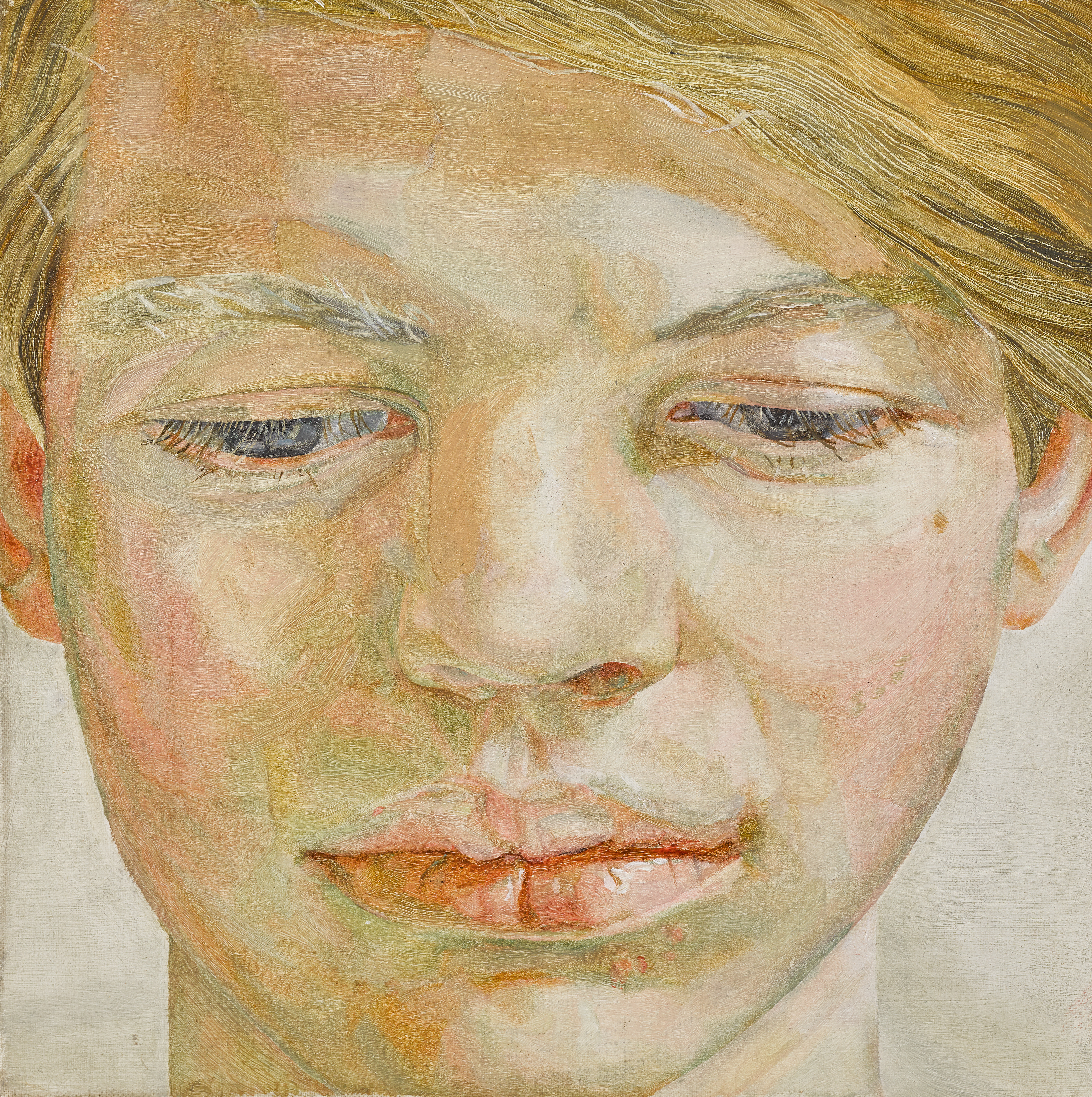 A close up portrait of a rosy-cheeked young man looking down