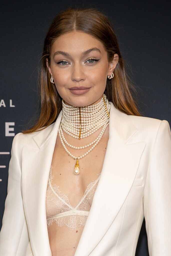 Gigi Hadid pairs her Jacquie Aiche pearl necklace with a white Versace suit and Fenty lingerie