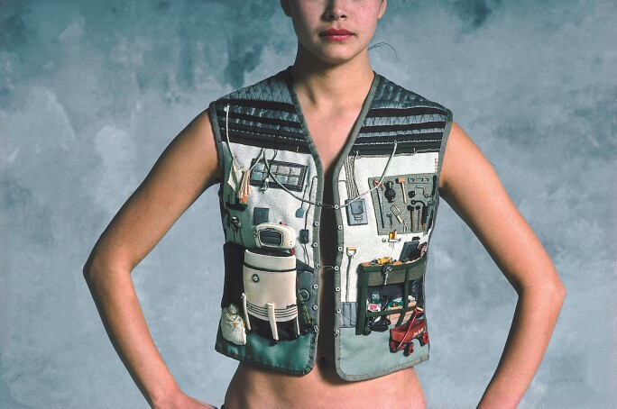woman in utility vest covered in found objects
