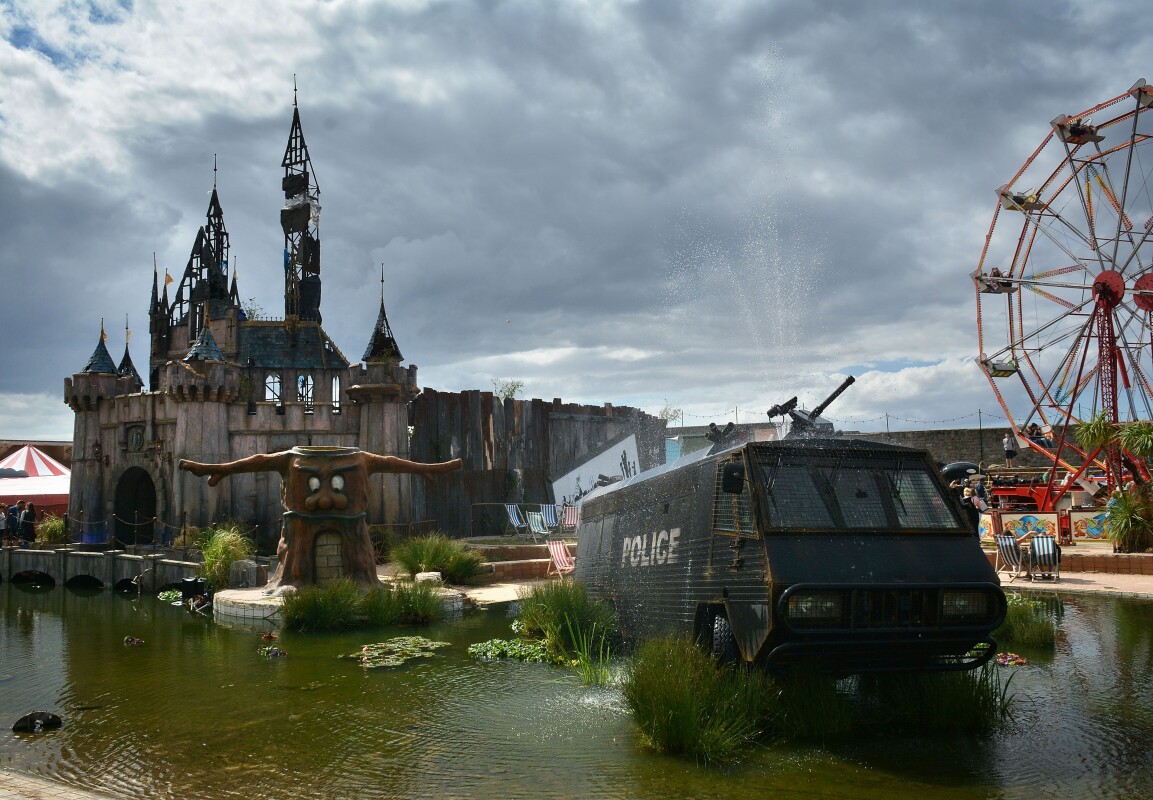 A fountain by Banksy, made from an abandoned police riot vehicle, is displayed in front of the fairy castle as Banksy's Dismaland Bemusement Park opens to the public, on August 28, 2015 in Weston-Super-Mare, England.