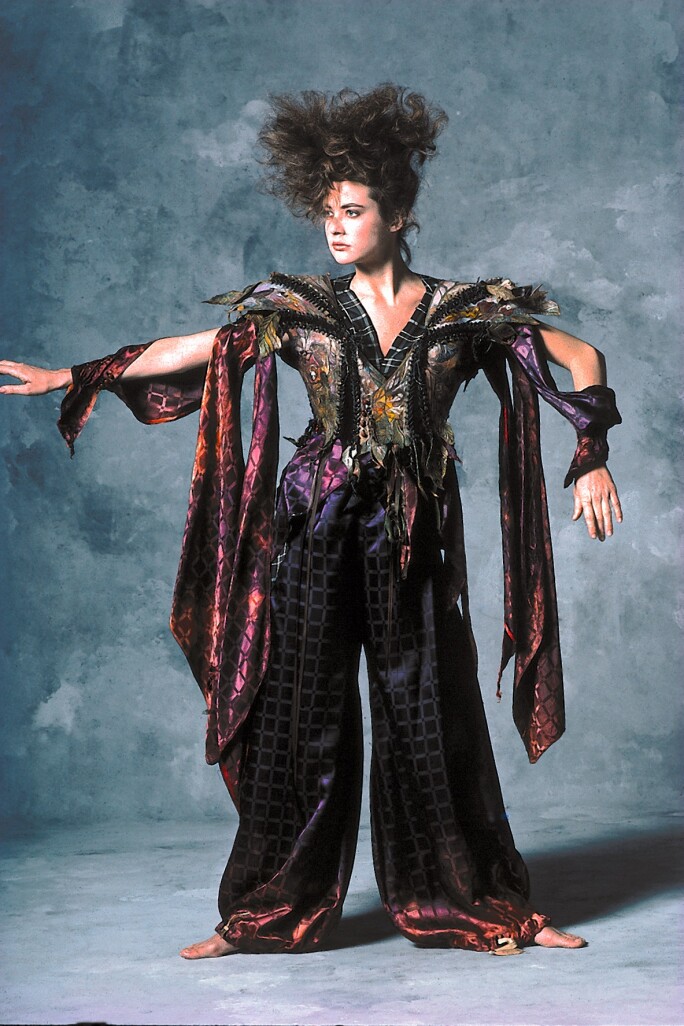 a woman in a shiny one piece of tooled, painted, laced, and stitched leather, suede, antique shoe buttons, and satin.