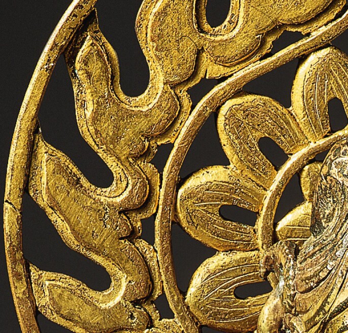 Detail of a golden sculpture of a buddha, focused on the area resembling a sun