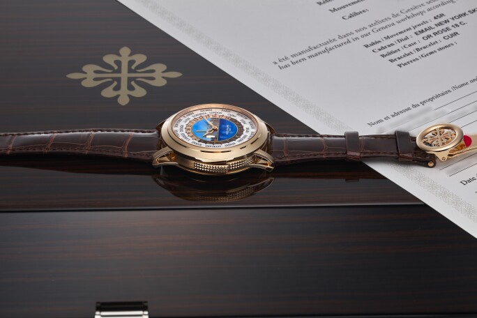 A gold watch with a leather strap on a wooden box