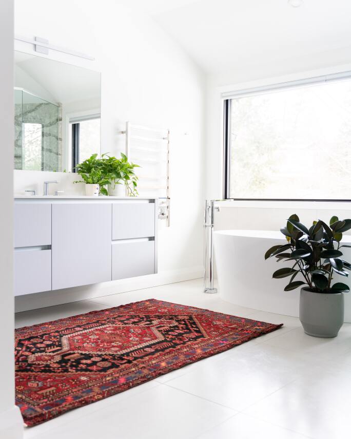 Photo of an antique rug in a white bathroom.