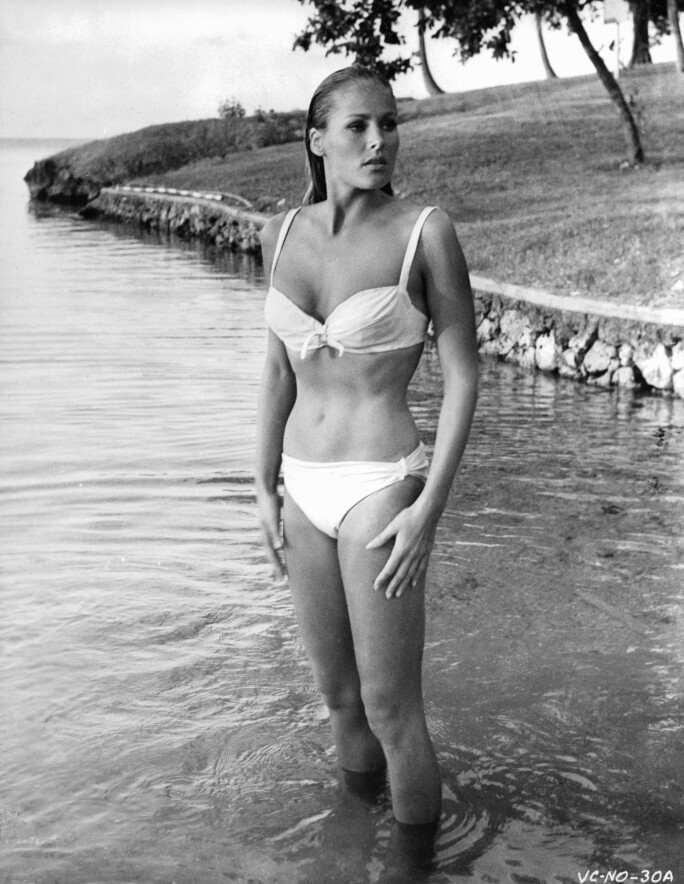 Ursula Andress In 'James Bond: Dr. No' emerging from water, wearing a white bikini.