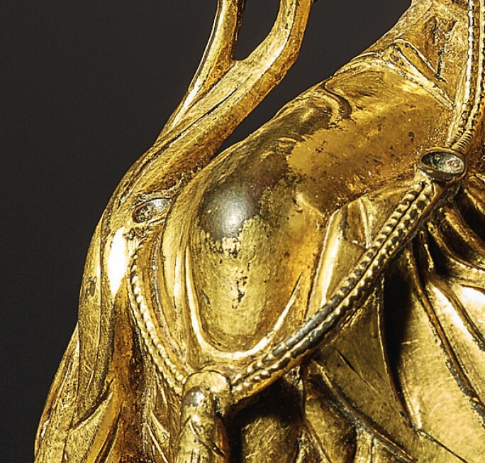 Detail of golden statue depicting a buddha, focused on the area resembling a knee
