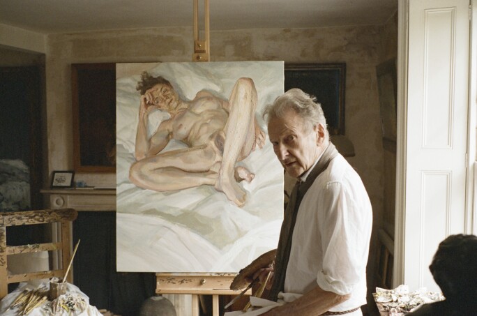 Lucian Freud standing in front of one of his nude portraits.