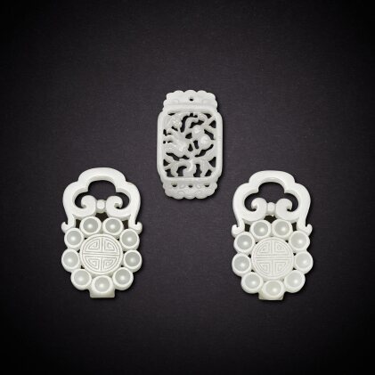View 1 of Lot 6936: A pair of white jade 'longevity' belt buckles and a white jade reticulated 'bat and fruits' pendant, Qing dynasty, 18th - 19th century | 清十八至十九世紀 白玉壽字帶扣一對及白玉鏤雕福壽雙全珮一件