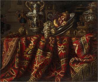 View 1 of Lot 33: Still life with pomegranates, grapes and assorted orfèvrerie on a table draped with an ornate Turkish carpet